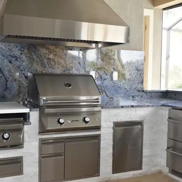 Modern kitchen with stainless steel grill, range hood, granite backsplash, and island counter