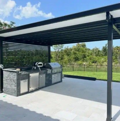 Covered outdoor patio with built-in grill and outdoor kitchen beside a green lawn