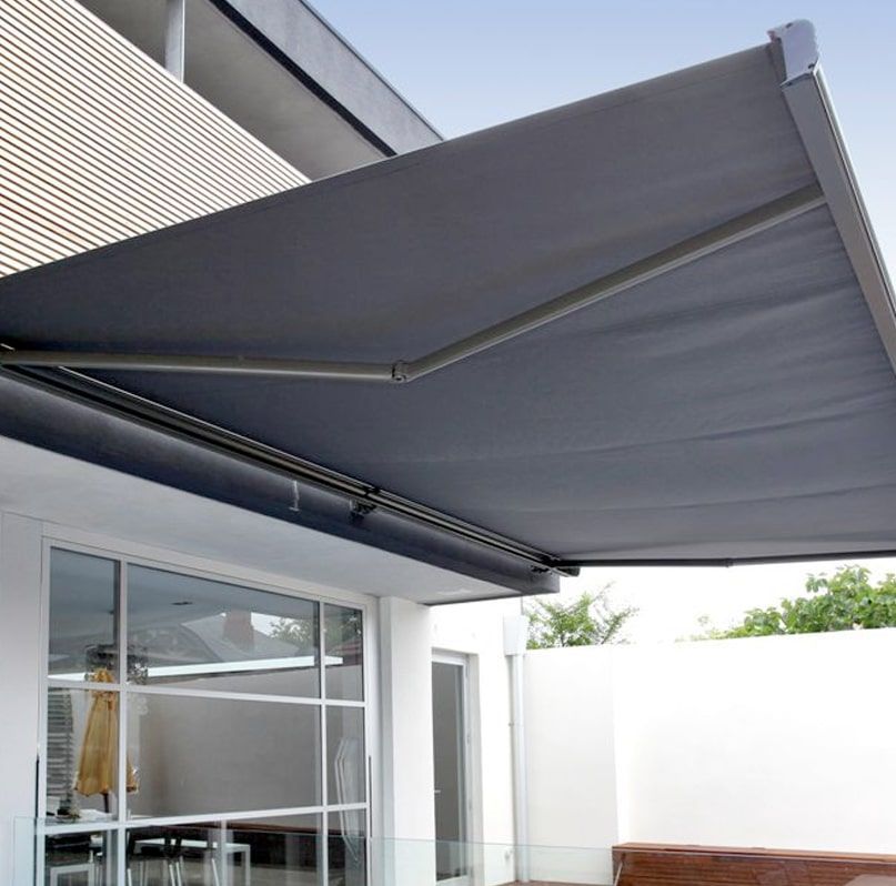 Gray retractable awning extending over a white patio beside a house