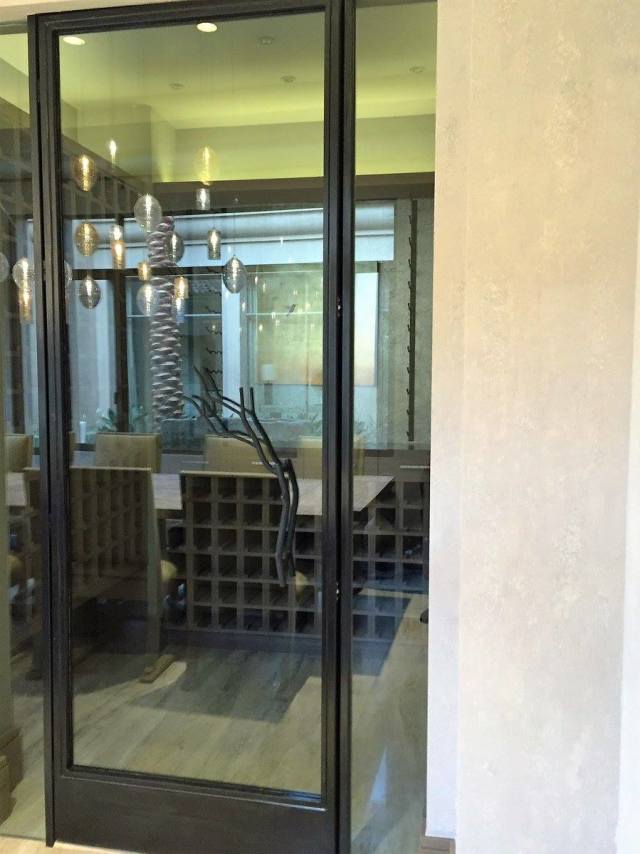 Glass door entrance to a dining area with a wine rack visible; modern decor.