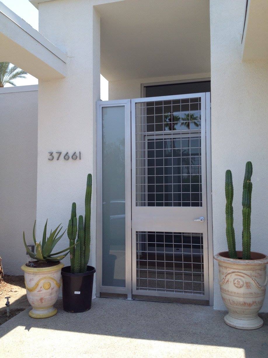Aluminum gate with geometric design, flanked by potted cacti and address 37661 on stucco wall.