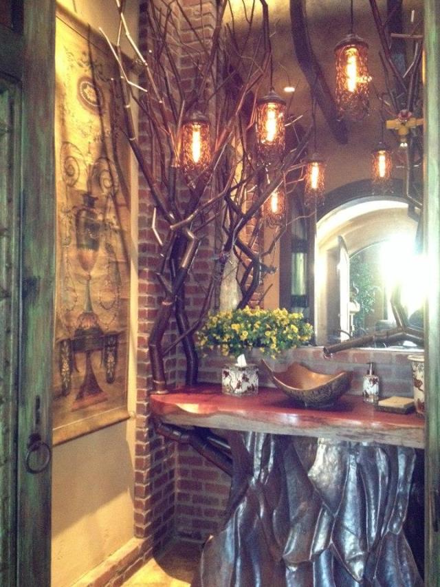 Rustic bathroom with tree trunk vanity, brick wall, and hanging lights.