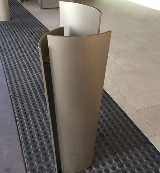Beige curved metal barrier on a gray textured walkway, likely for pedestrian guidance.