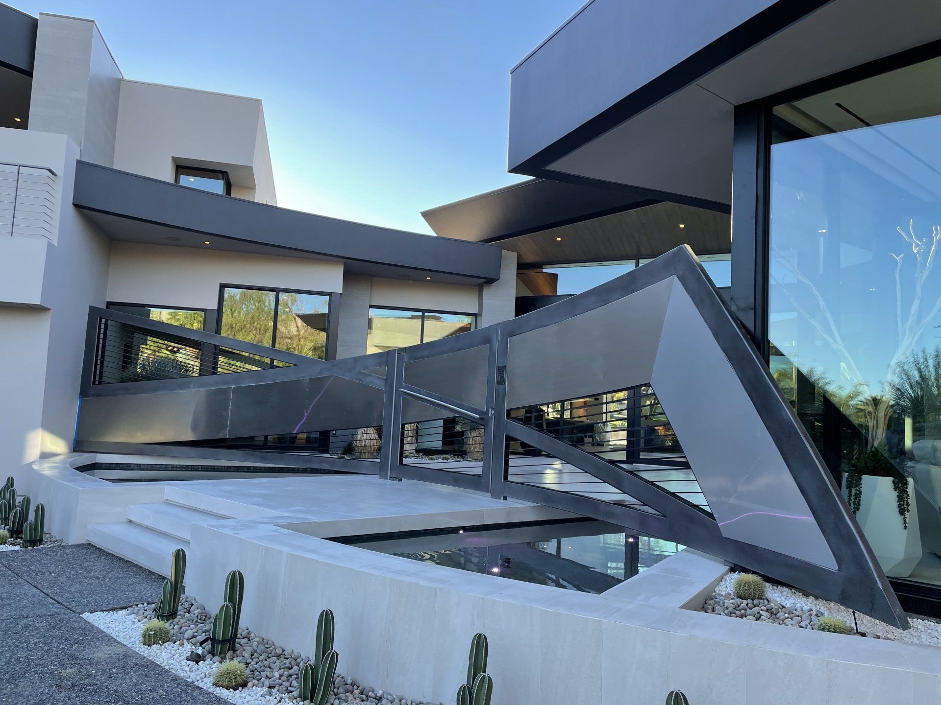 Modern home with geometric gray accents and a reflective pool in the foreground.
