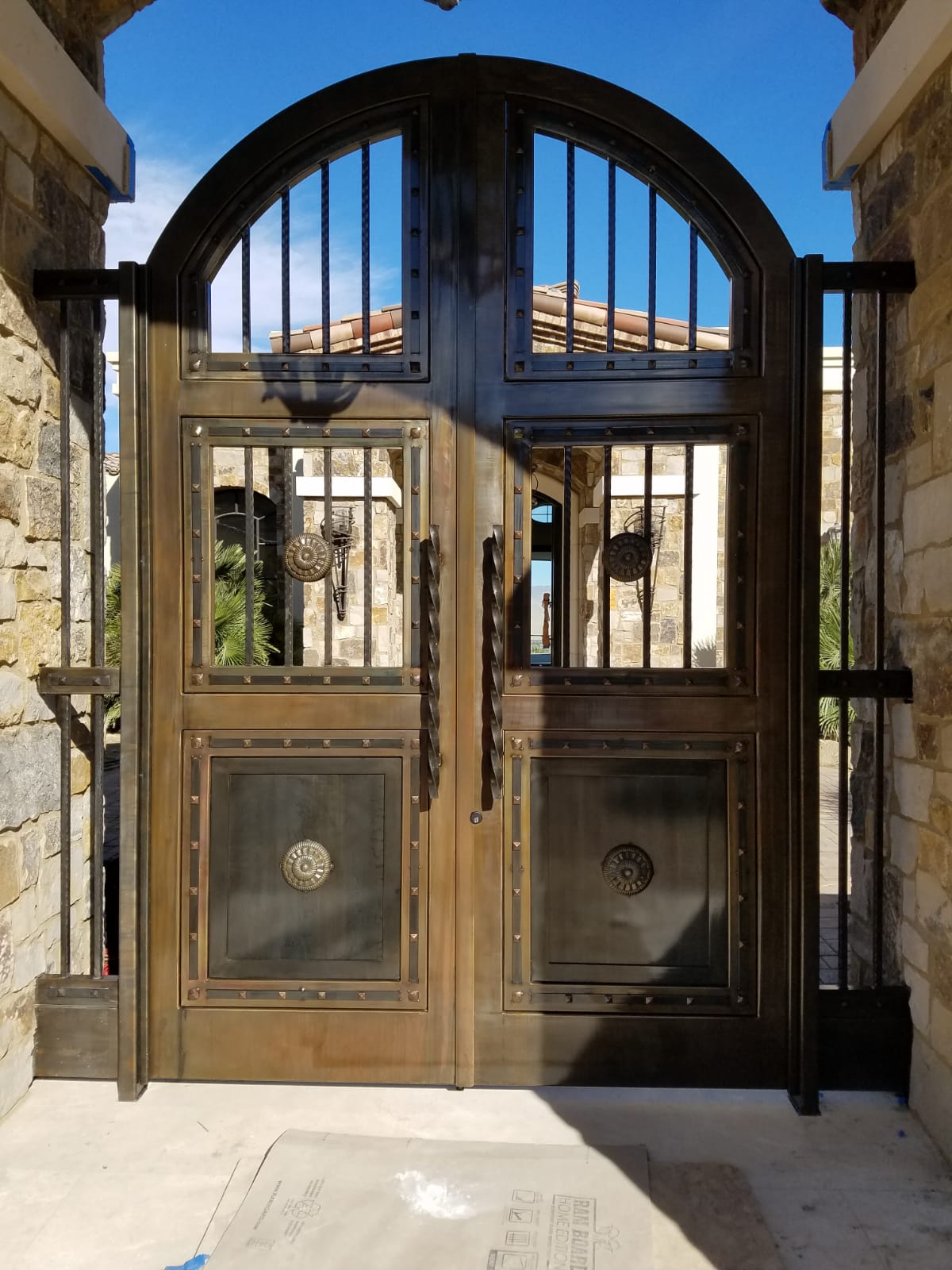 Bronze double doors with arched top and vertical bars. Stone columns frame the entryway.