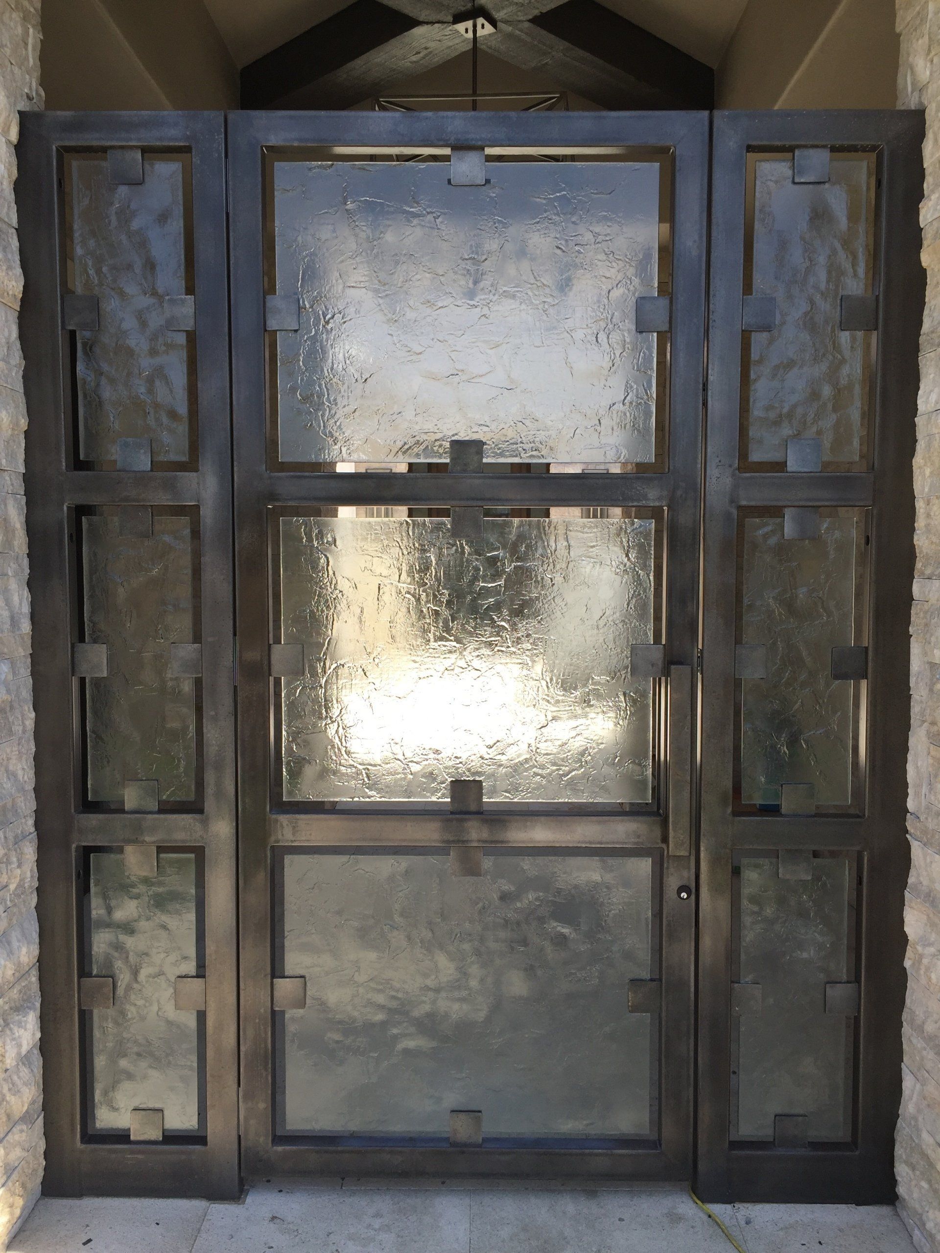 Dark metal gate with textured glass panels.