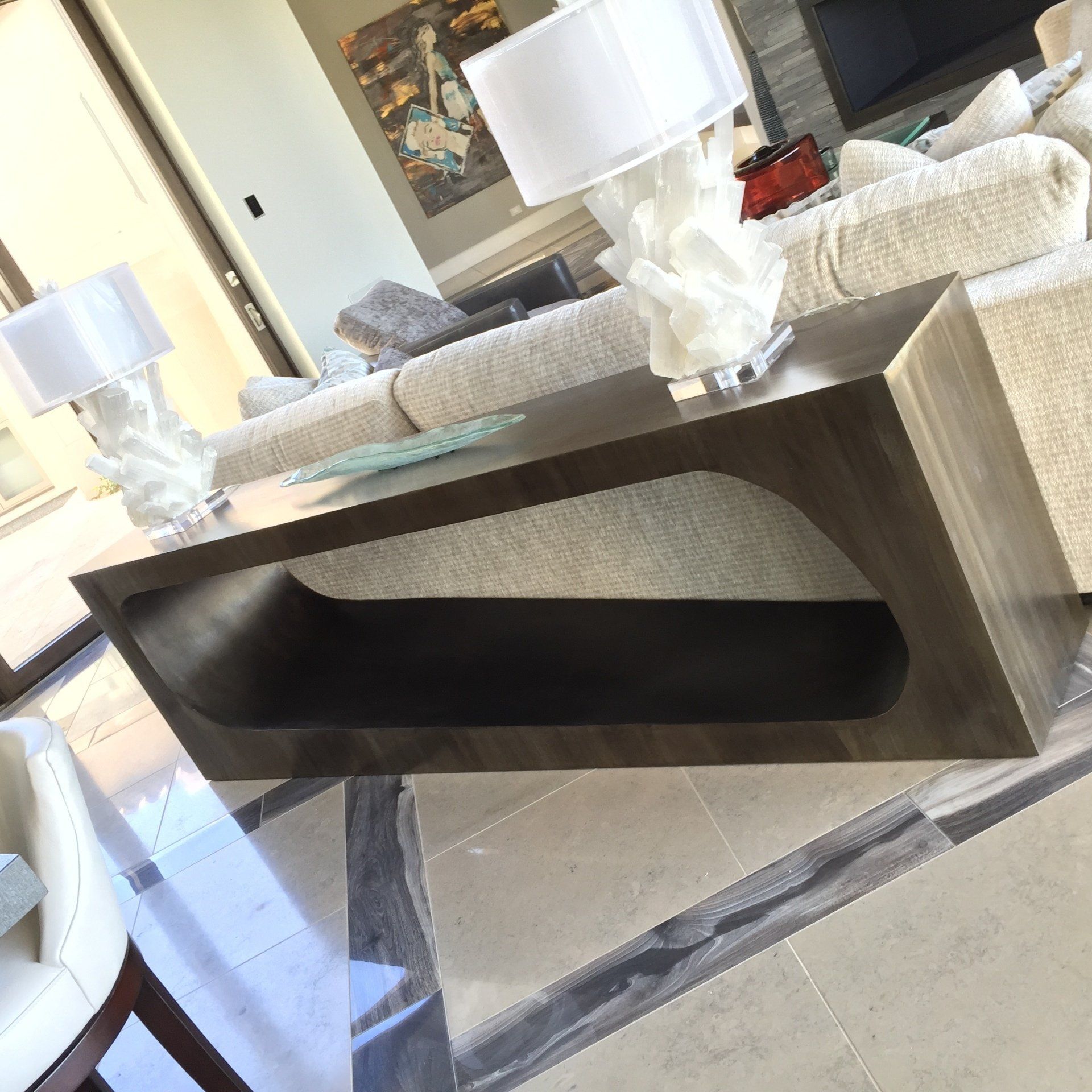 Wooden coffee table with cutout, lamps, and a sofa in a modern living room.