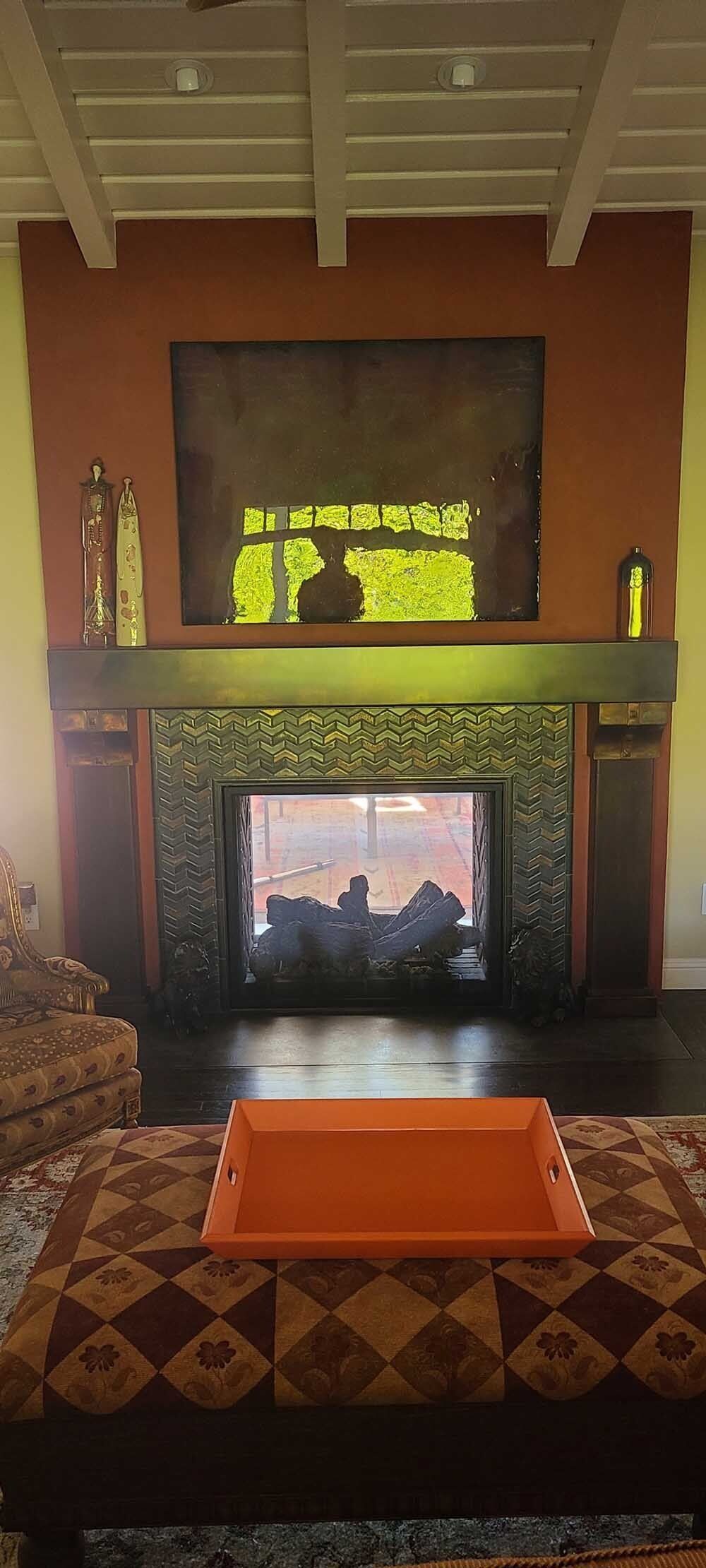 Fireplace with orange tray on patterned ottoman.