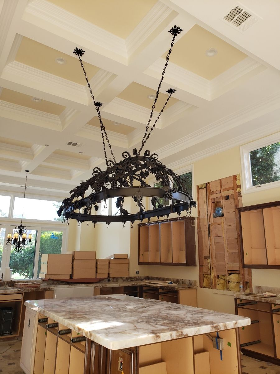 Kitchen under construction with a large chandelier hanging above the island countertop.