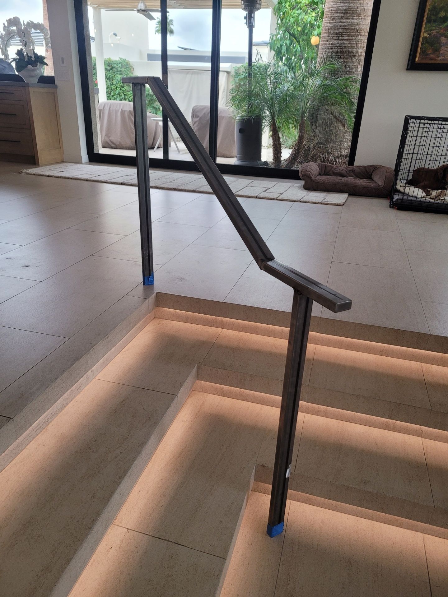 Modern stairs with a dark metal handrail; step lighting; interior setting.