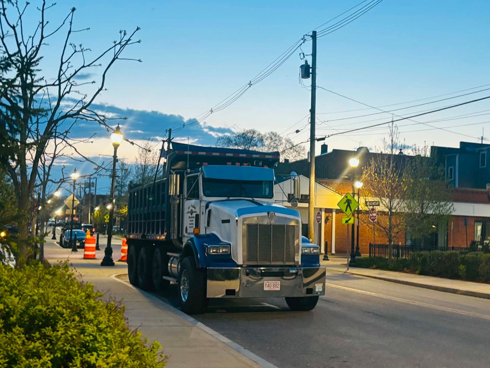 Residential street with parked trucks, sidewalk, and row houses under a blue sky