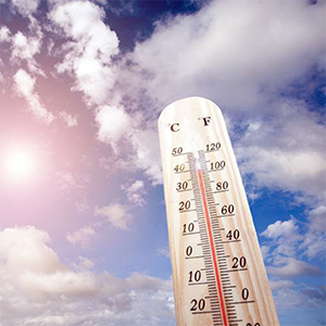 Thermometer against a blue sky with clouds, indicating a high temperature above 100 degrees Fahrenheit.