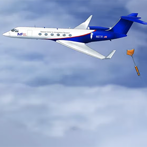 Jet aircraft in blue and white, National Center for Atmospheric Research. Releasing a weather instrument with an orange parachute.