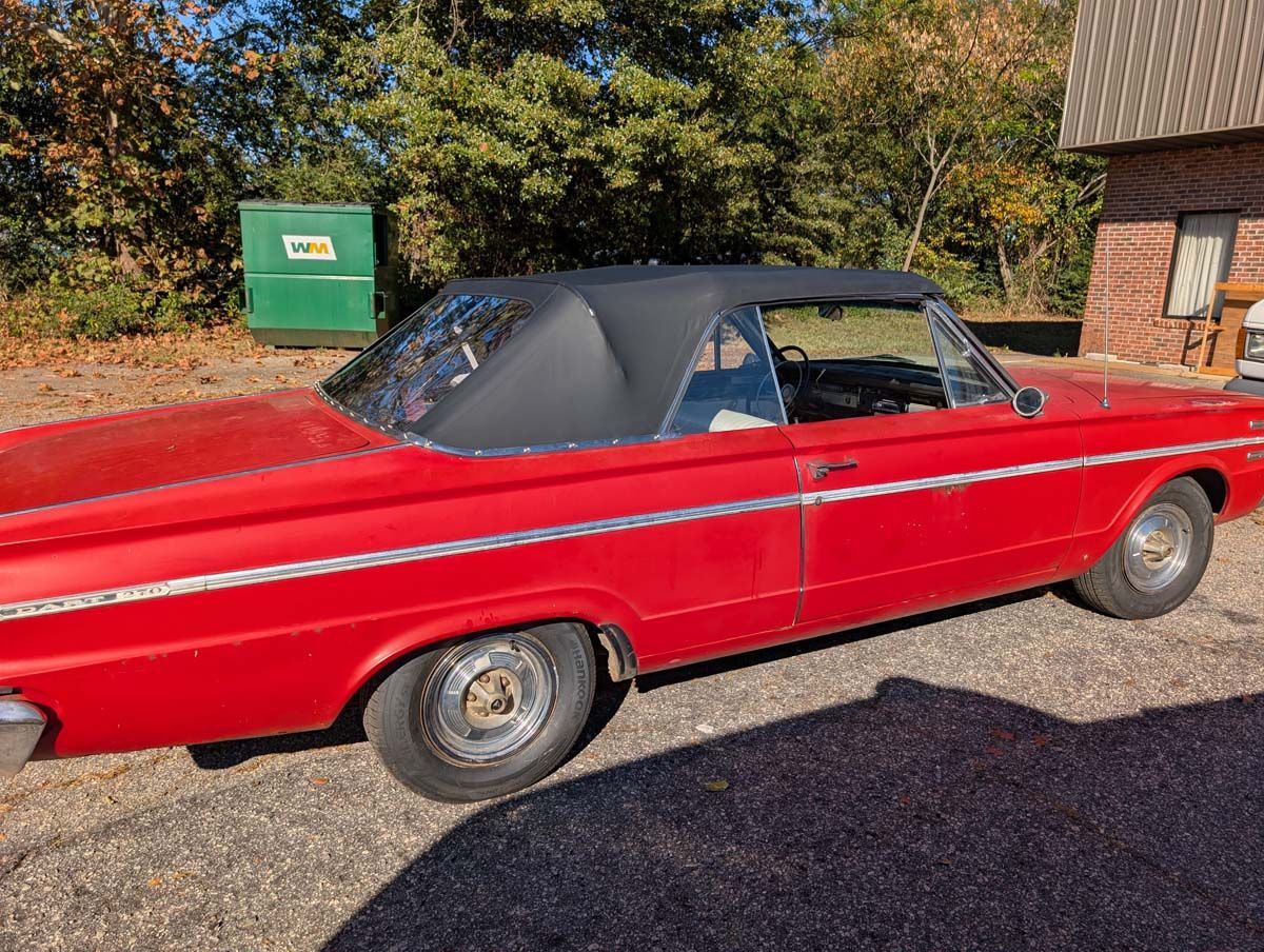 Red convertible car with a black top parked outdoors.