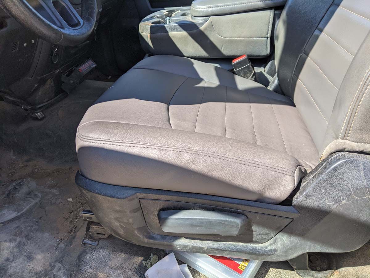 Close-up of a vehicle's brown leather seat, showing stitching and a seat adjustment lever.