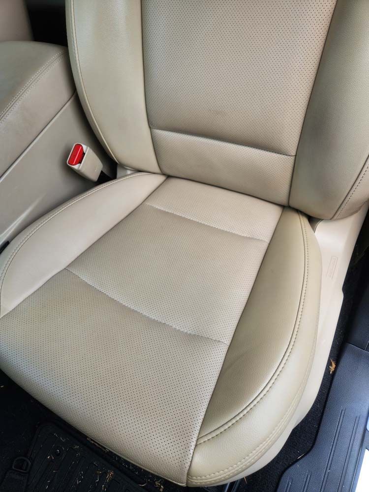 Beige leather car seat with perforated backrest and seat.
