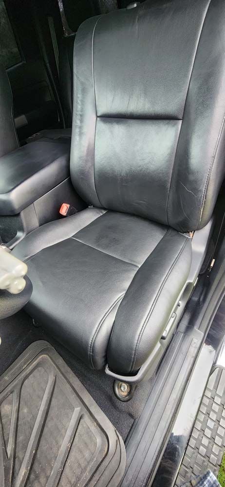 Black leather car seat with a black floor mat.