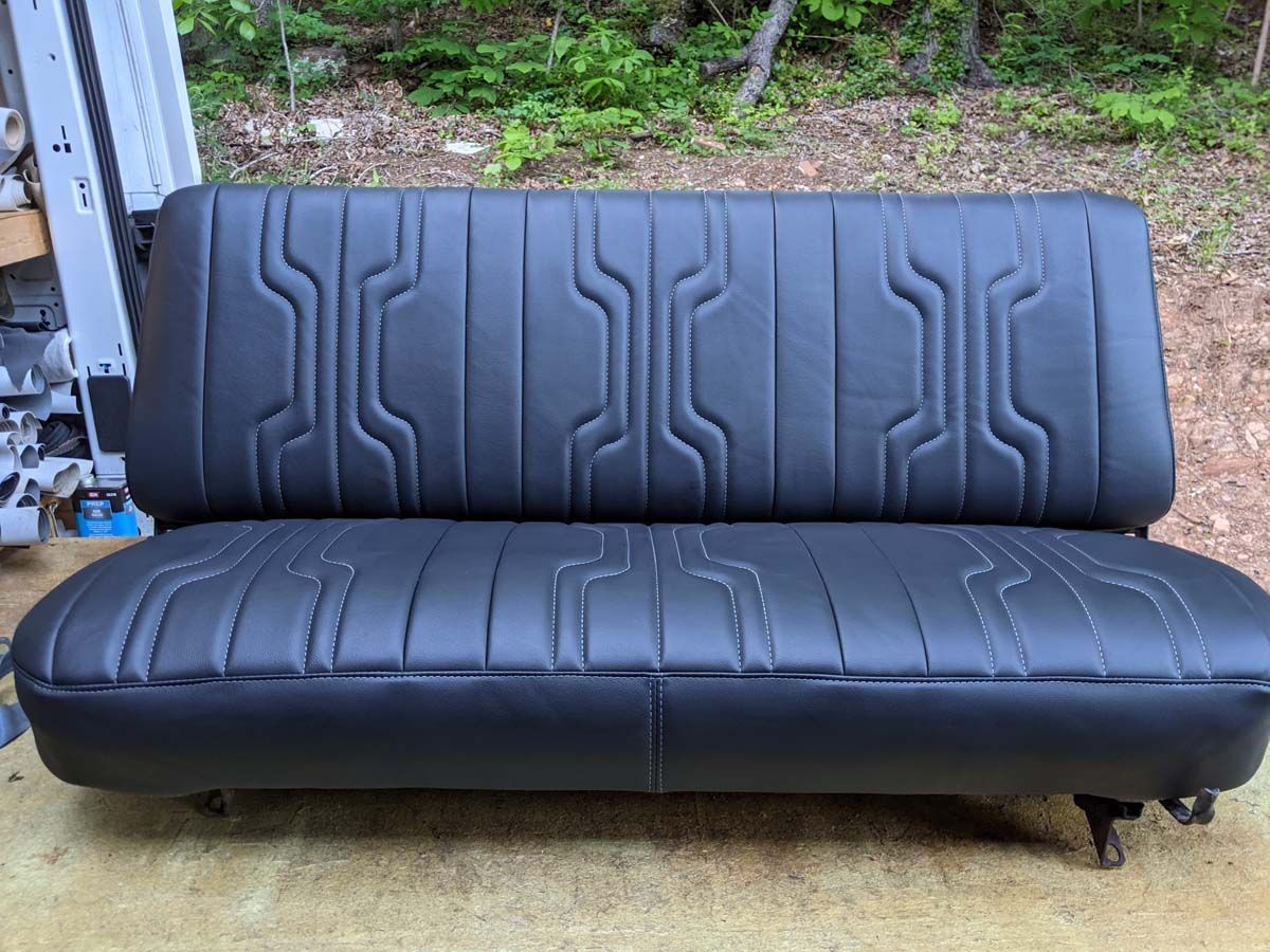 Black vinyl bench seat with geometric stitching on a wooden surface.