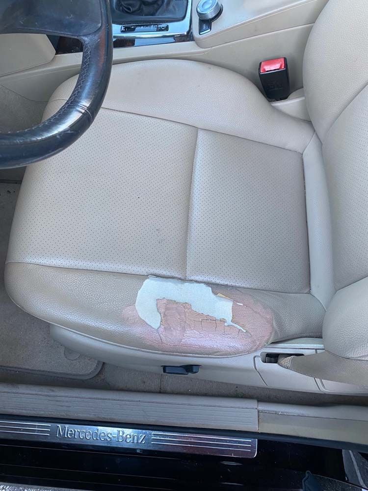Beige car seat with damaged leather peeling on the bottom cushion. Mercedes Benz logo visible.