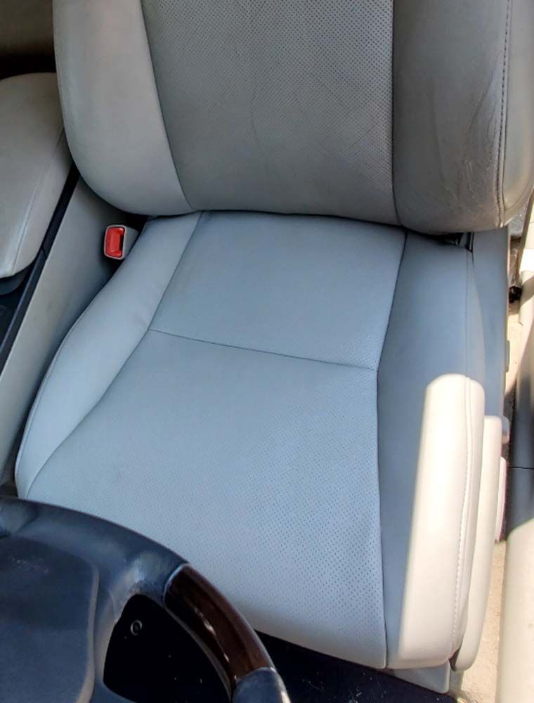 Light gray leather car seat with a red seatbelt buckle.