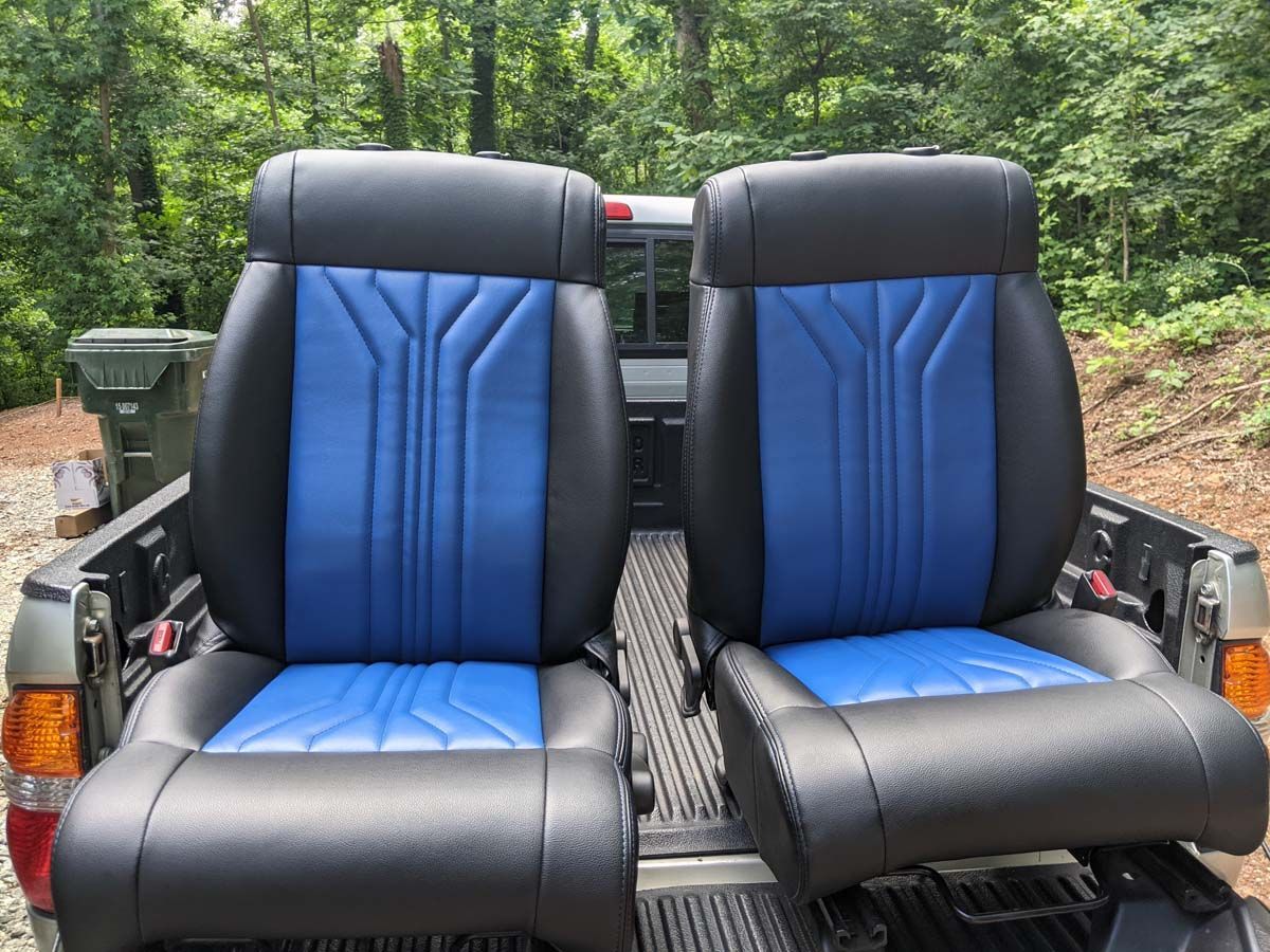 Two black and blue car seats in a truck bed.