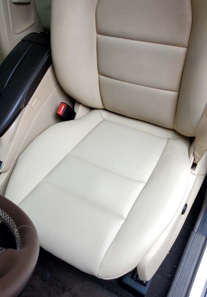 Beige leather car seat with visible stitching and a seatbelt.