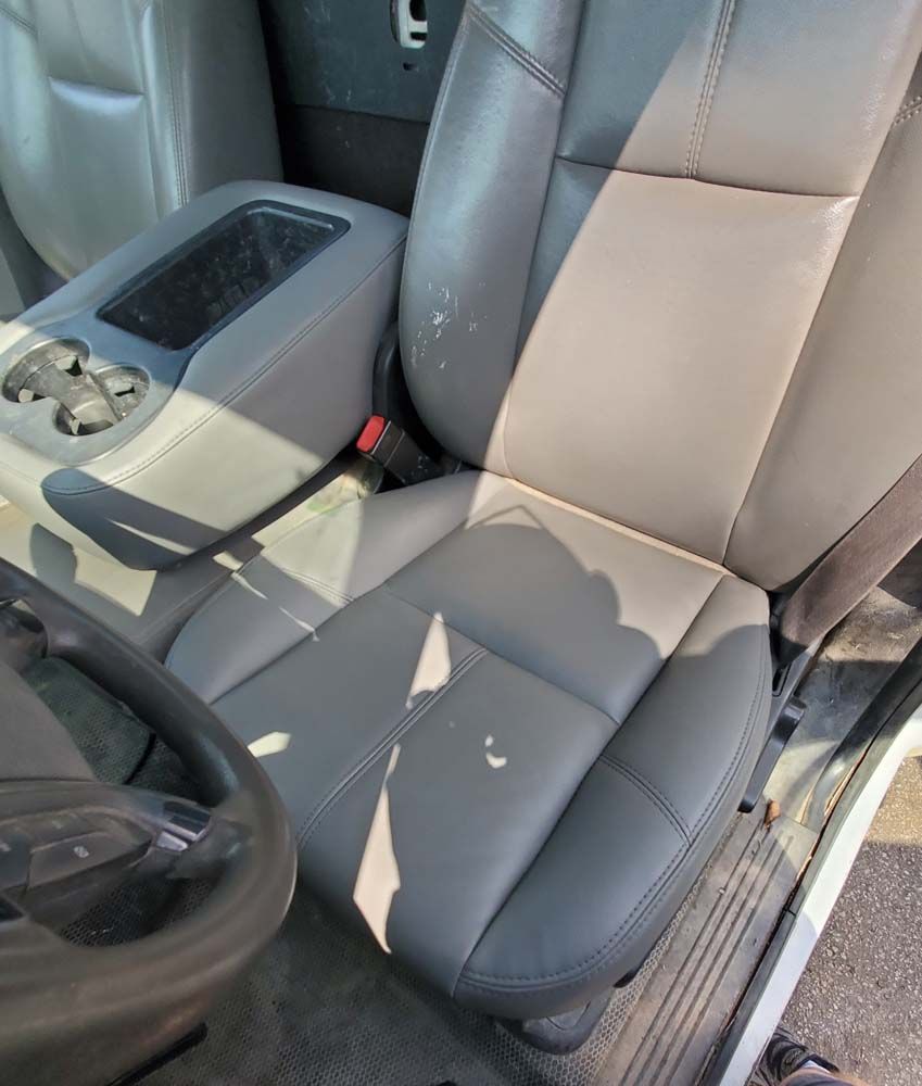 Gray leather car seat with white paint splotches and built-in console.