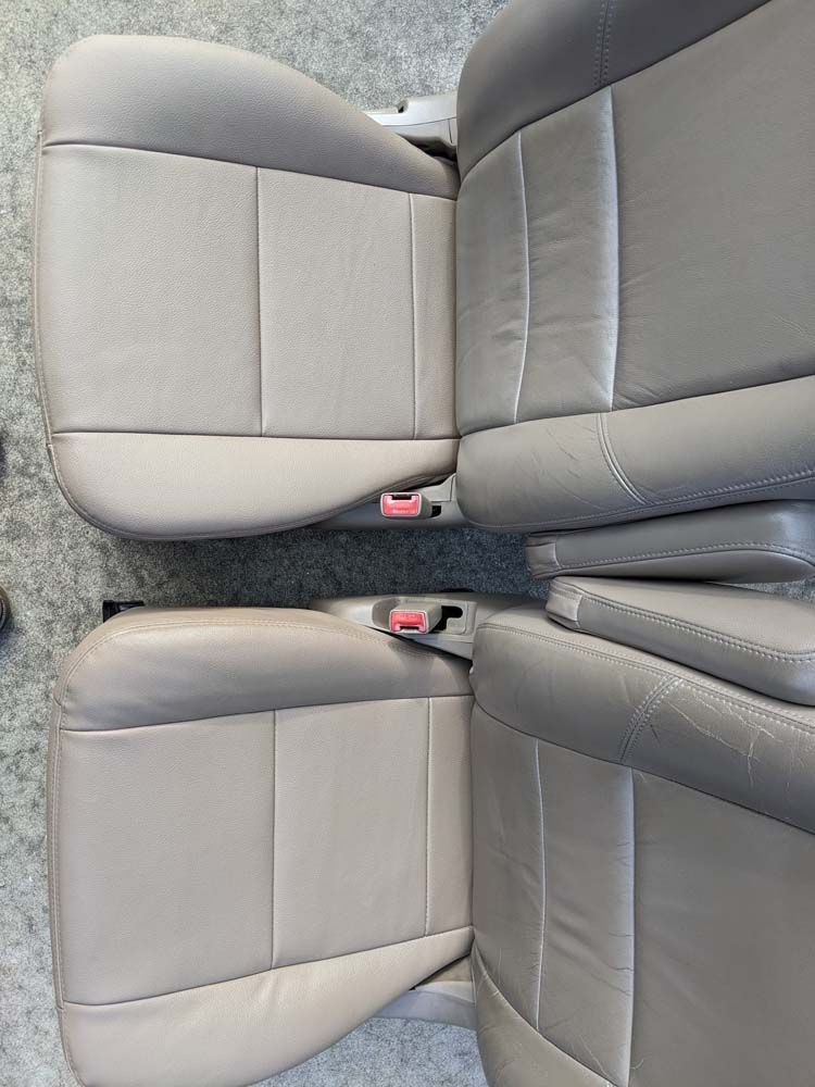 Two light gray car seats side by side, showcasing their upholstery and seatbelt latches.
