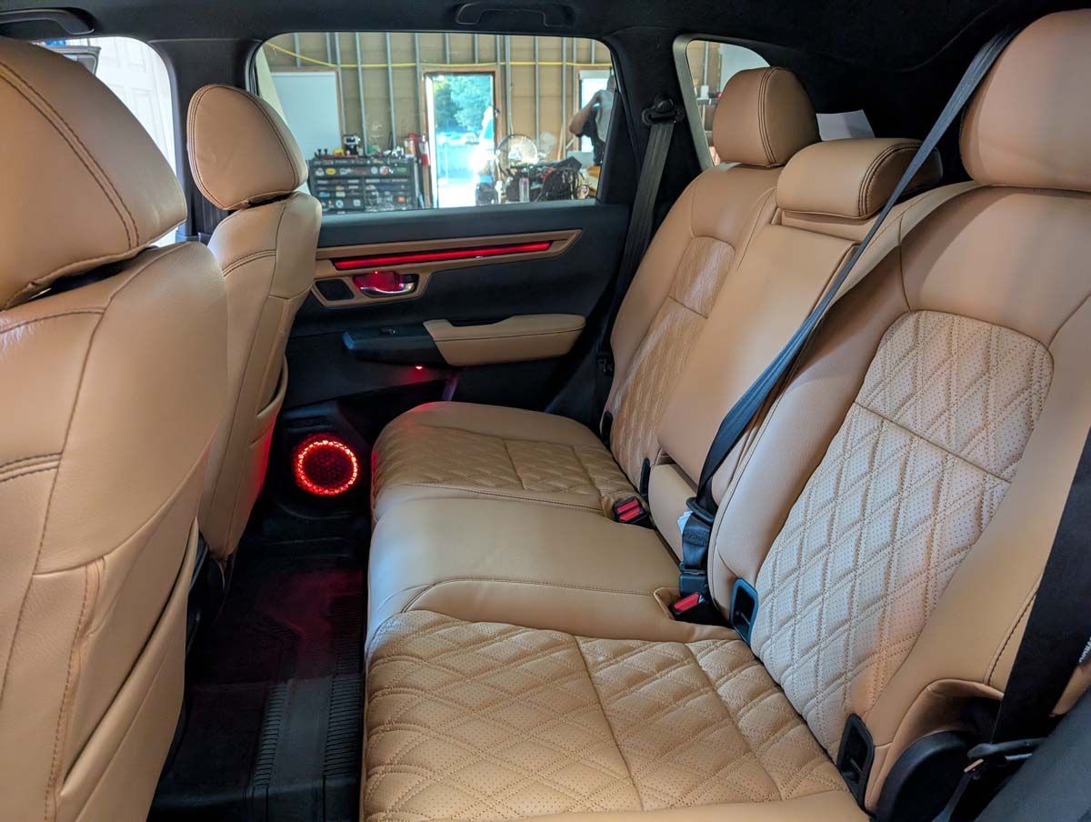 Tan leather interior of a car with diamond-stitched seats and red ambient lighting.