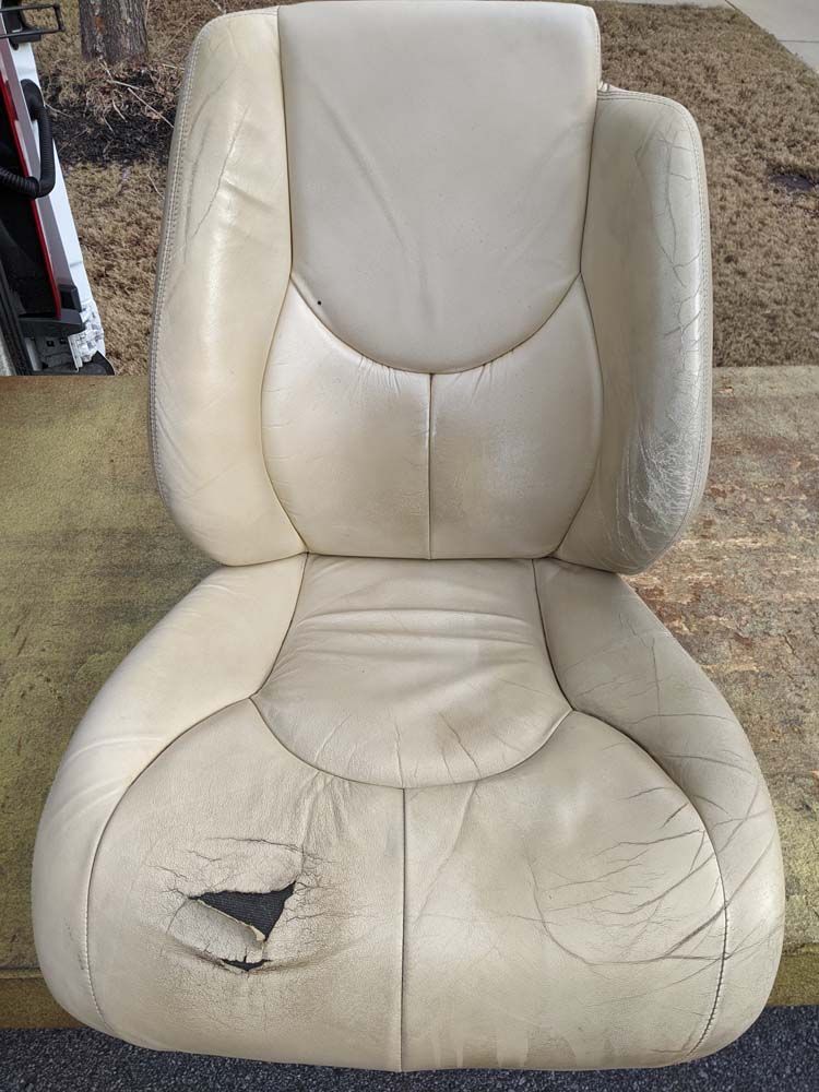 Beige leather car seat with significant wear and a large tear.