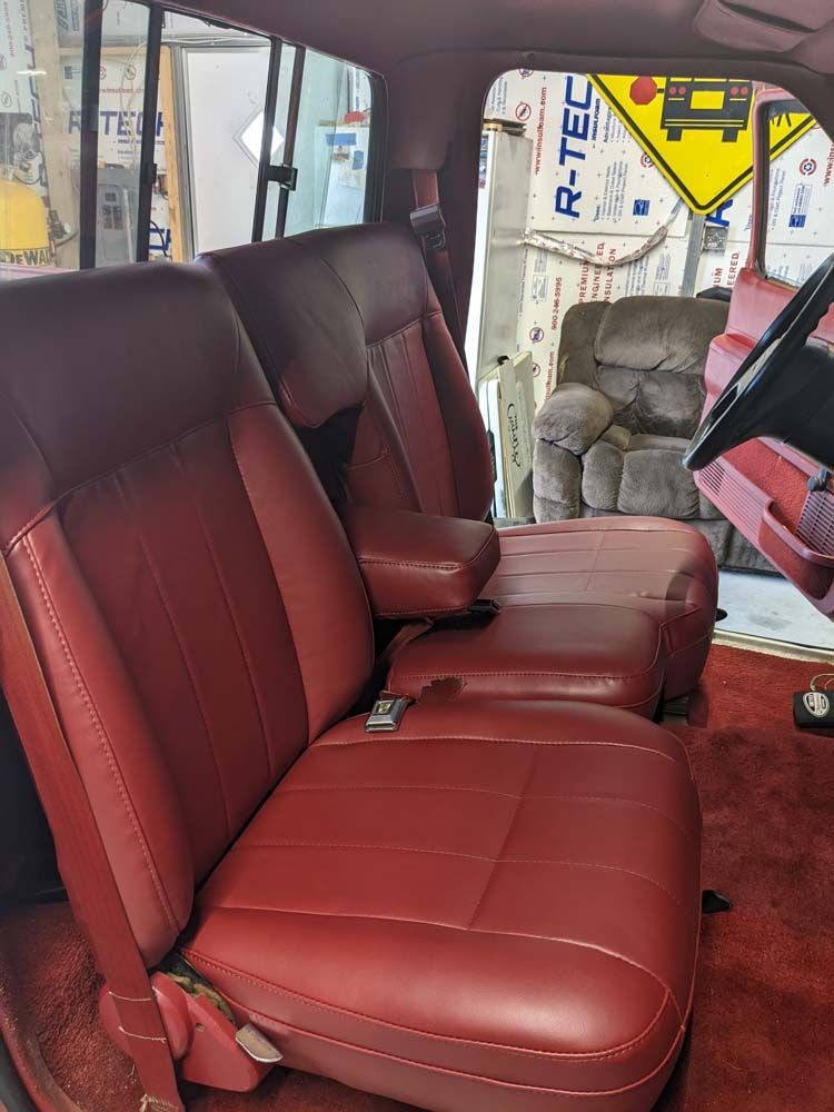 Maroon leather truck seats; armrest between them. Red carpet and steering wheel visible.