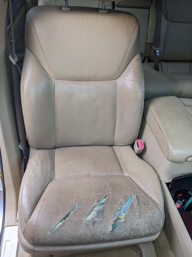 Beige car seat with three large tears.