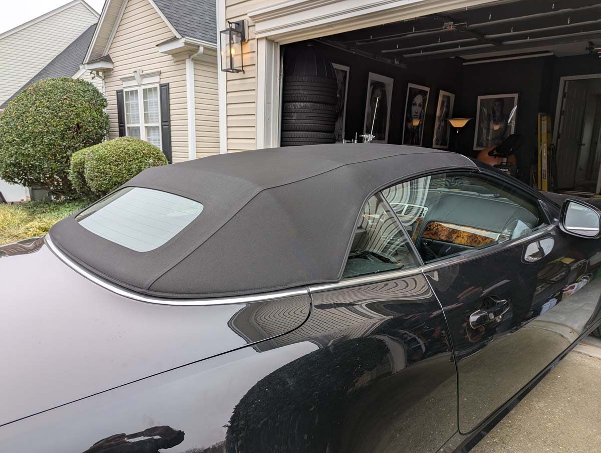 Black convertible car parked in a garage with its top up.