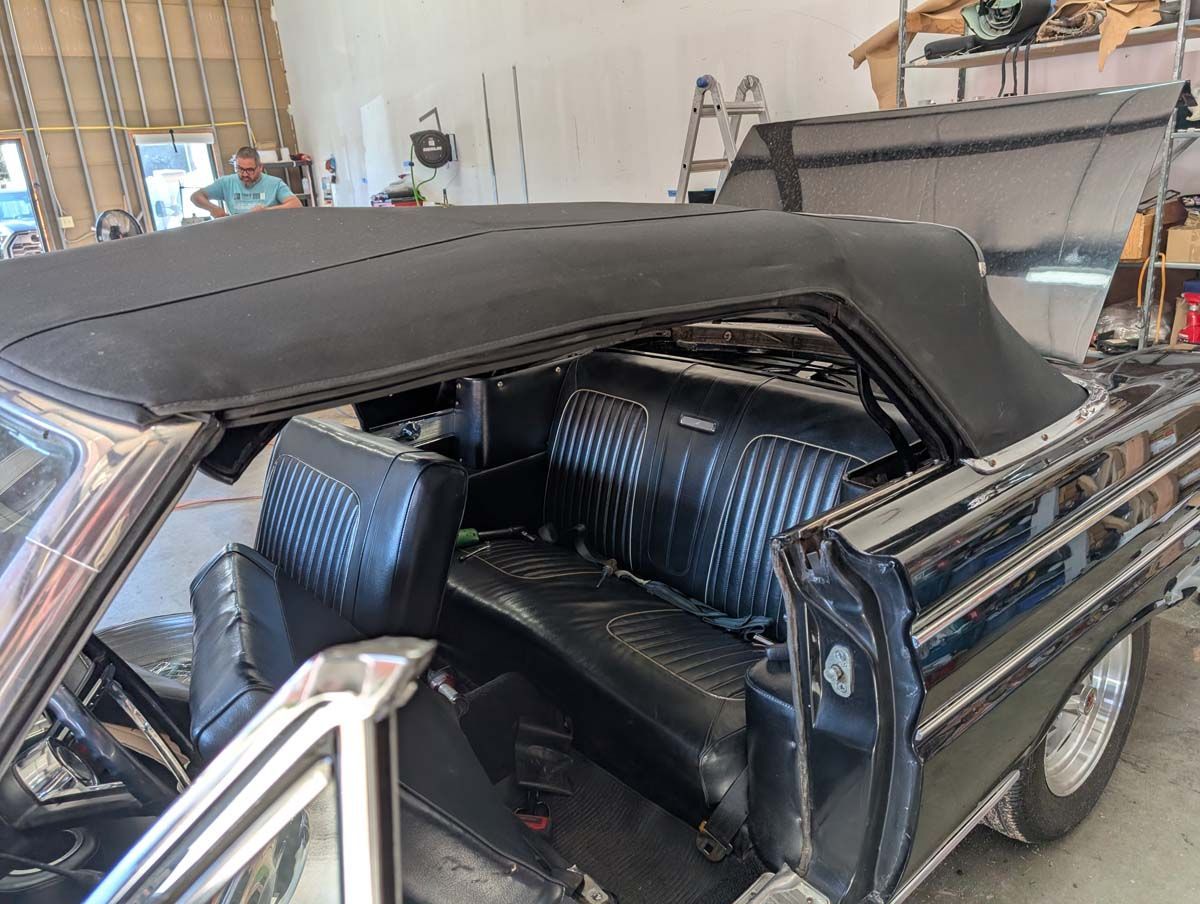 Black convertible car interior with black seats and a person in the background.