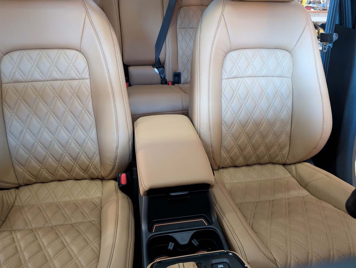 Tan leather car interior with quilted seats and center console with cup holders.