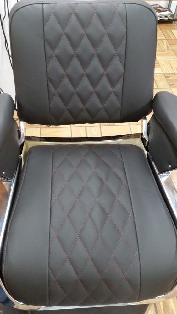 Black barber chair with diamond-stitched leather on the back and seat, chrome arms and frame.
