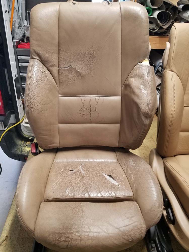 Tan leather car seat showing significant wear and tear, with rips and flaking.