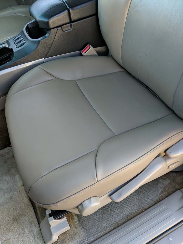 Beige car seat with black stitching, near center console and door.