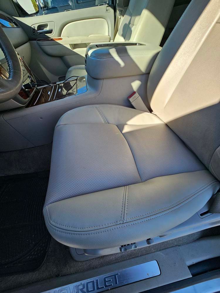 Beige leather car seat with perforated detailing and a center console.