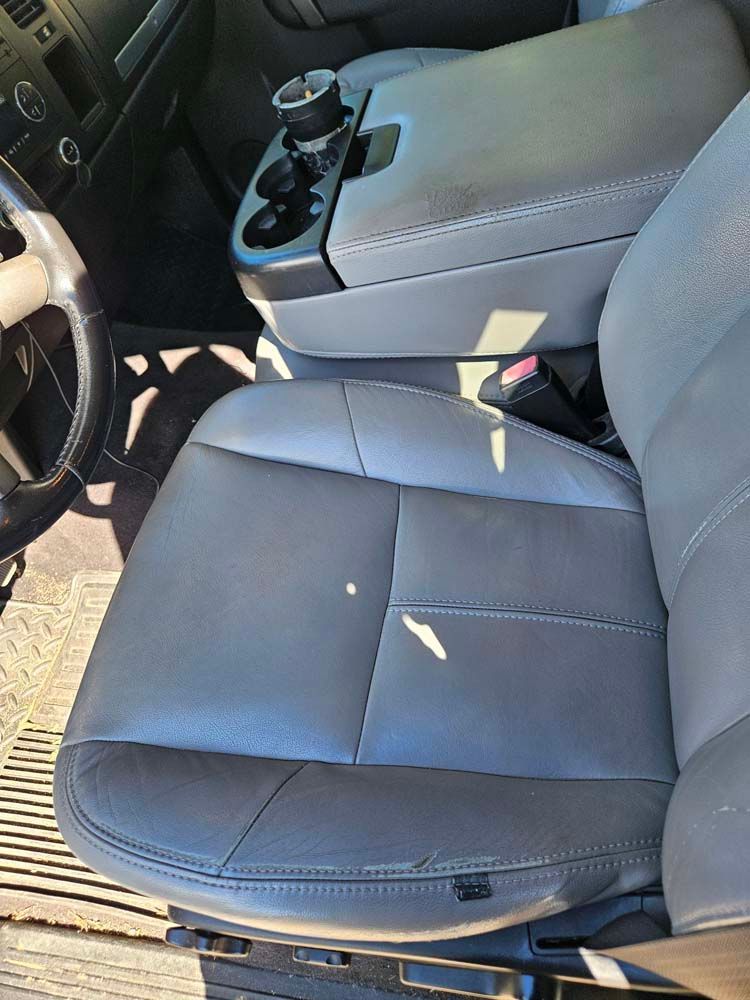 Gray leather truck seat with center console and cup holders.