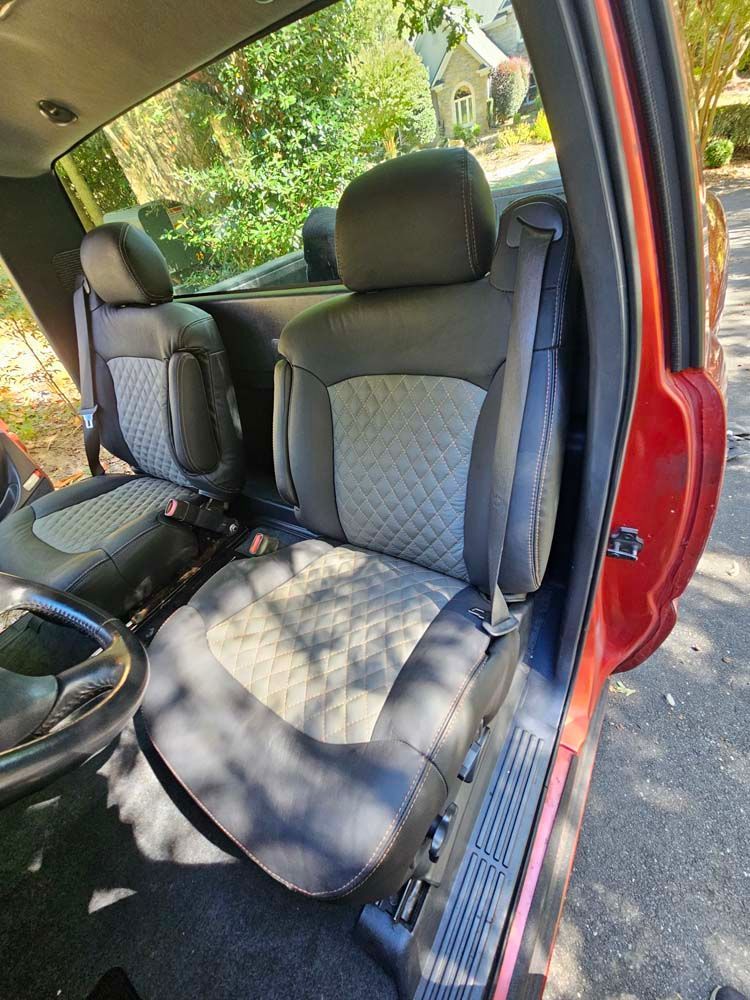 Interior of a red truck with black and gray custom seats. Seats have diamond pattern details.