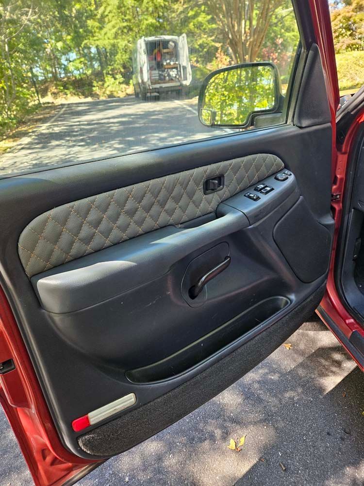 Red car door interior with gray quilted panel, black accents, and open to the outside.