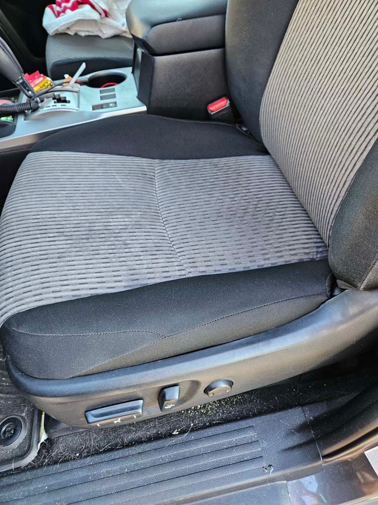Car seat with gray and black fabric, control buttons visible at base.