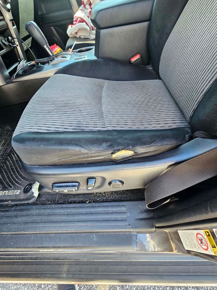 Gray and black car seat with worn fabric.