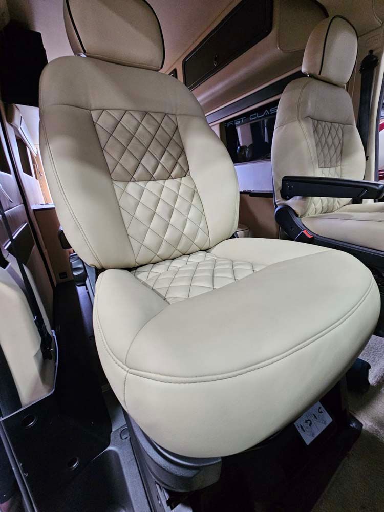 Beige leather car seat with diamond stitching, inside a vehicle.