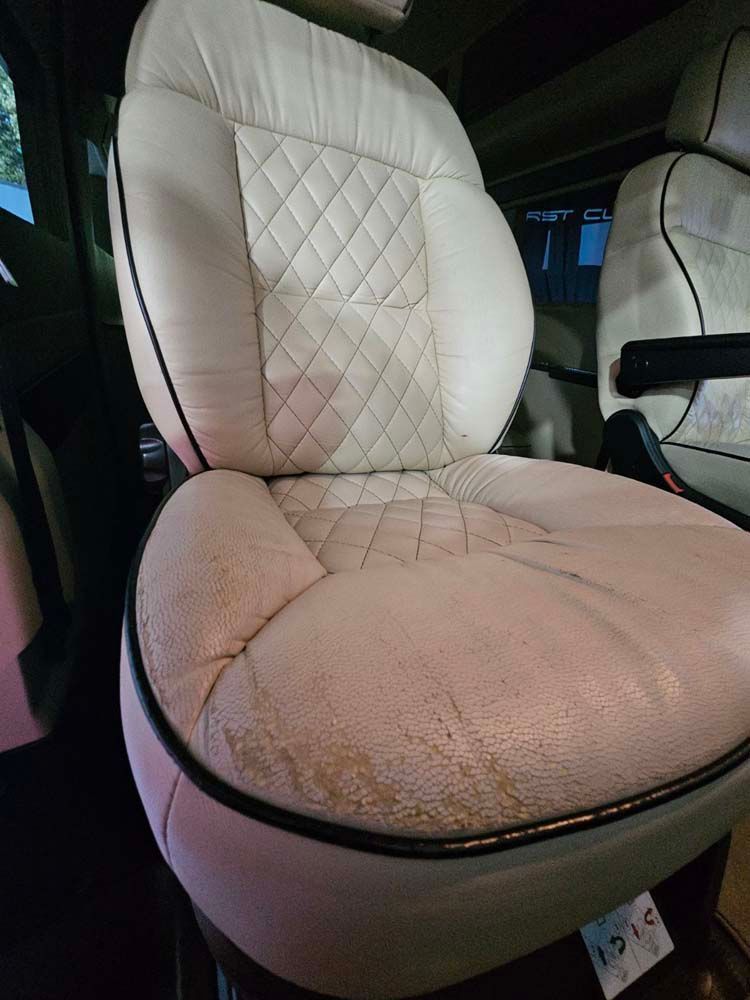 Cream-colored car seat with diamond stitching, black trim, and wear on the seat bottom.