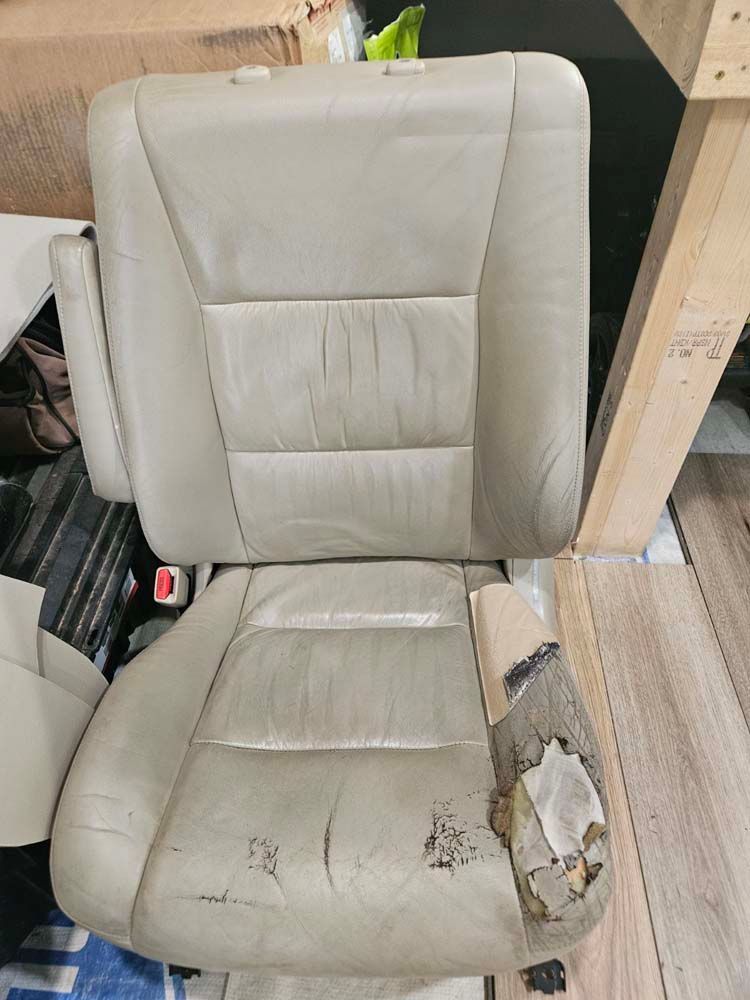 Tan car seat with damaged bottom cushion and armrest.