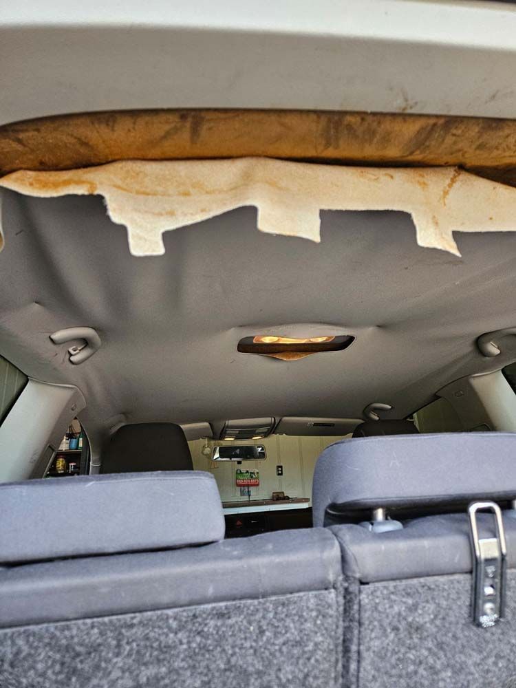 Interior car shot showing sagging headliner and exposed foam.
