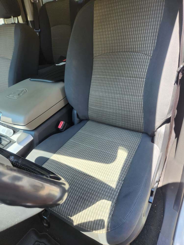 Gray and tan patterned car seat with black trim, console, and steering wheel.