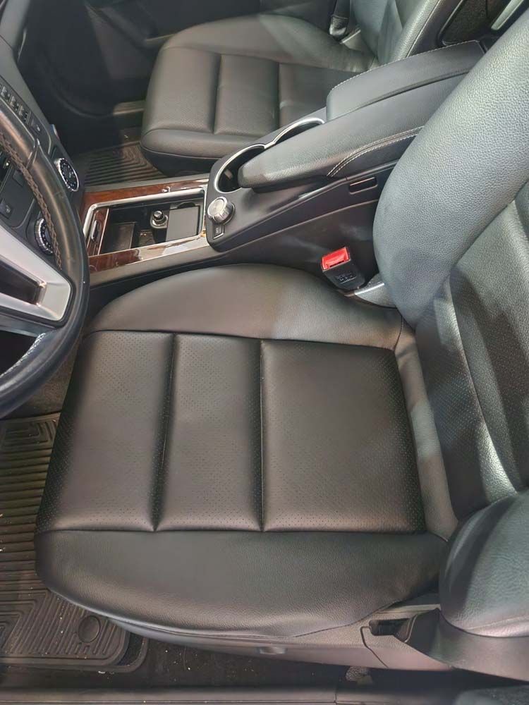 Black leather car seat with central console, cup holders, and armrest visible.